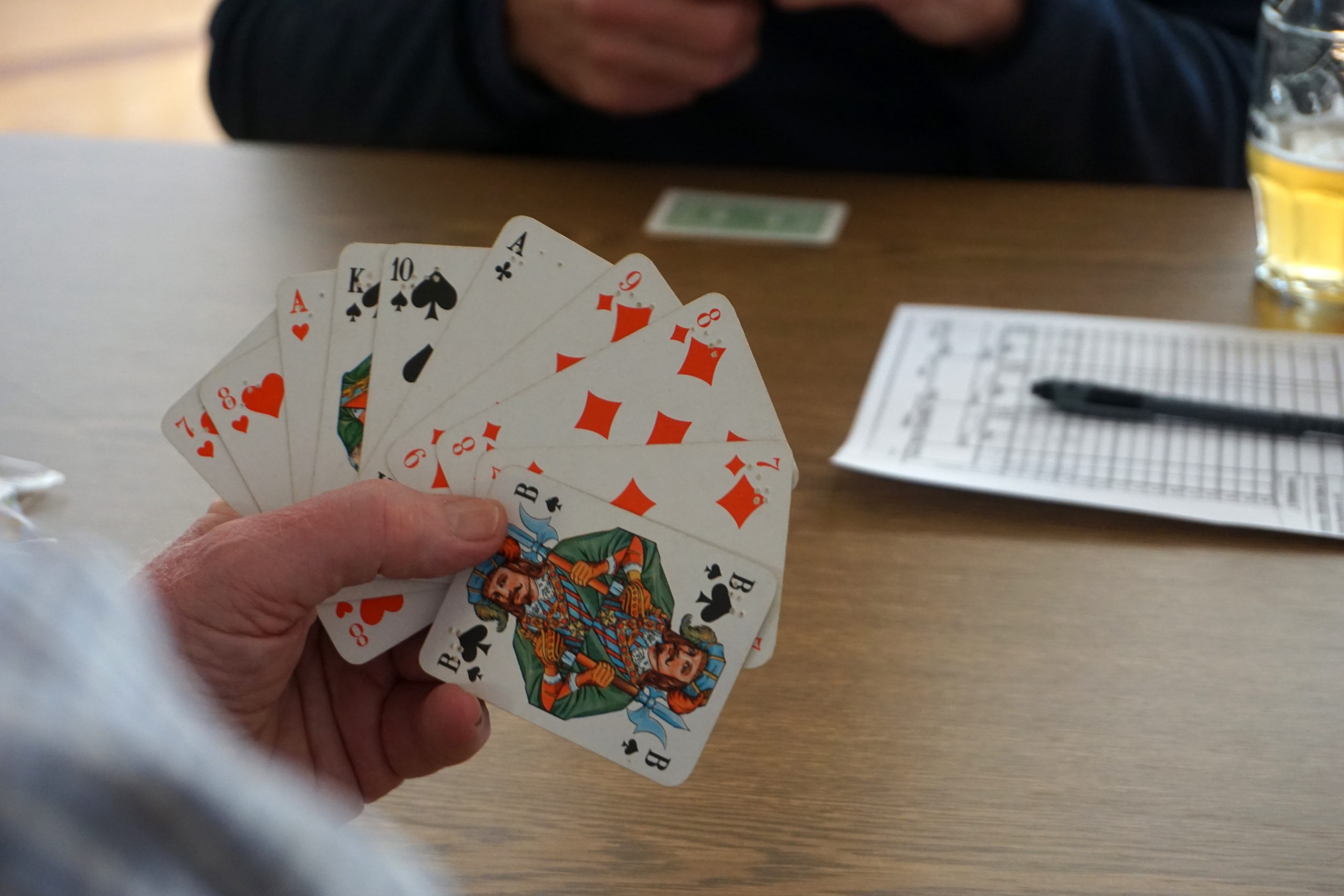 Eine Hand hält Skatkarten mit Brailleschrift.