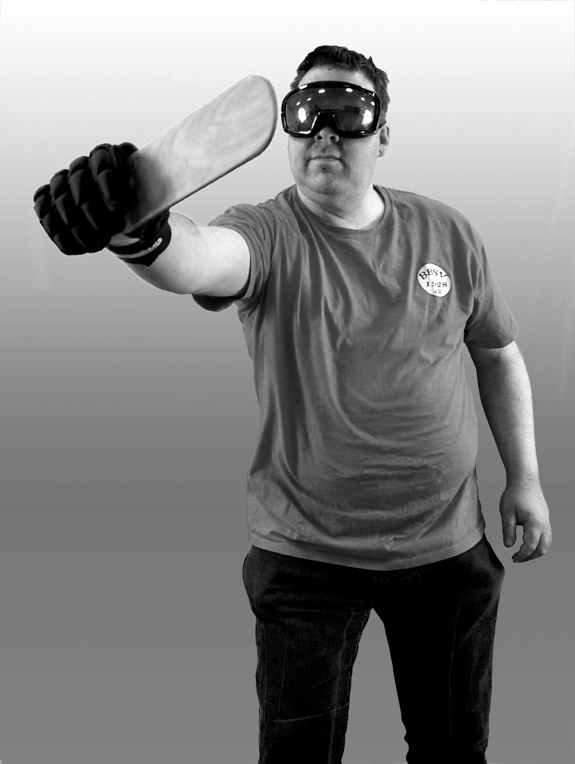Matthias Hübner hält in seiner rechten Hand einen Showdown-Schläger. Er trägt an dieser Hand einen schwarzen, festen Handschuh. Den Arm streckt er aus. Außerdem trägt er eine verdunkelte Skibrille und ein T-Shirt des BBSV.