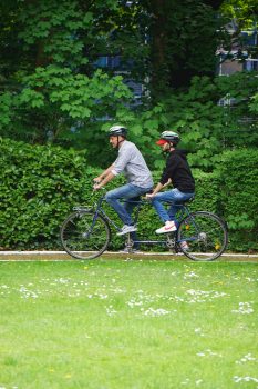 Zwei Männer mit Fahrradhelmen fahren Tandem.